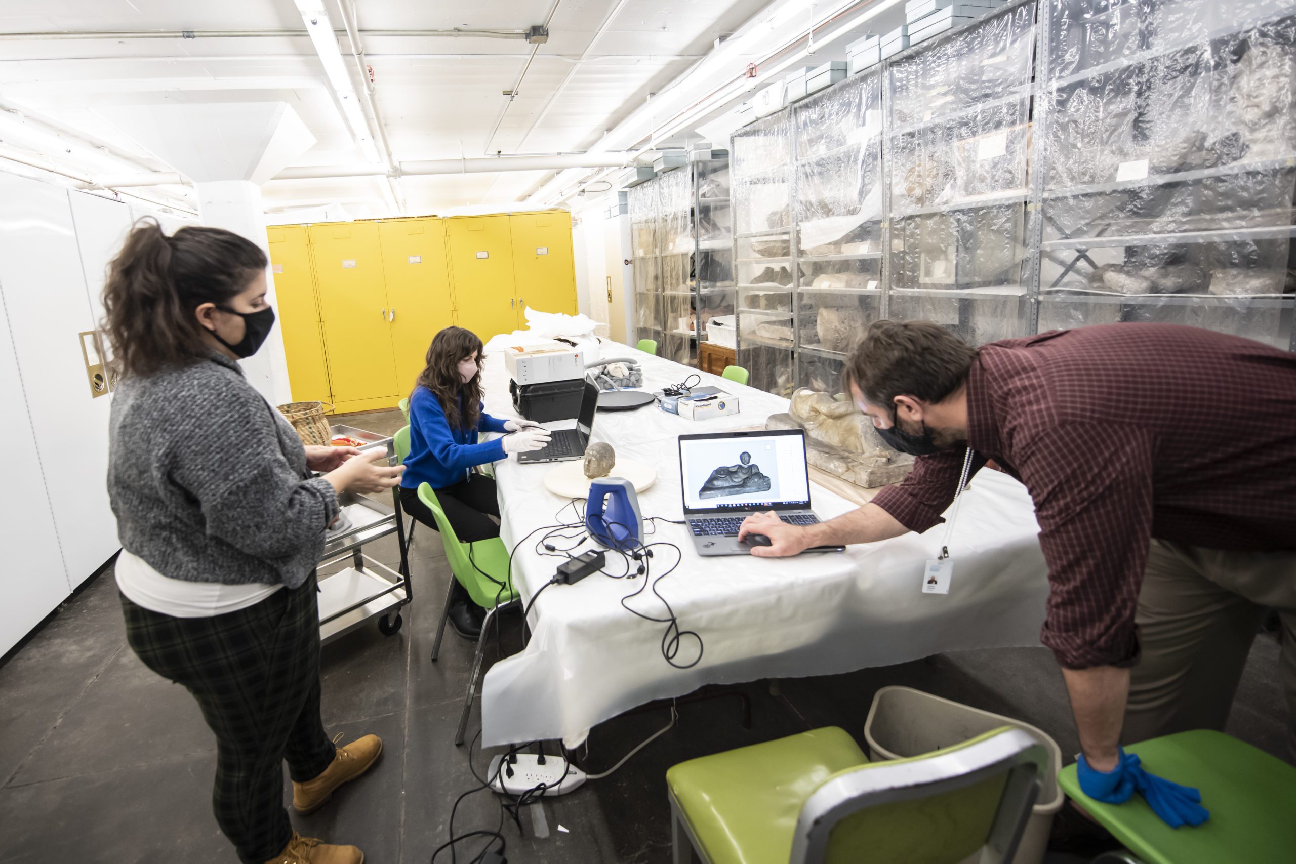 University Honors Cllege students Brianna Stellini, and Derek Wessel (red sweater)scan an Etruscan statue under the supervision of assistant cuator, Lisa Haney (blue) and faculty advisor Josh Cannon (button down) in a storage warehouse used by the Carnegie Museums. Devember 2021