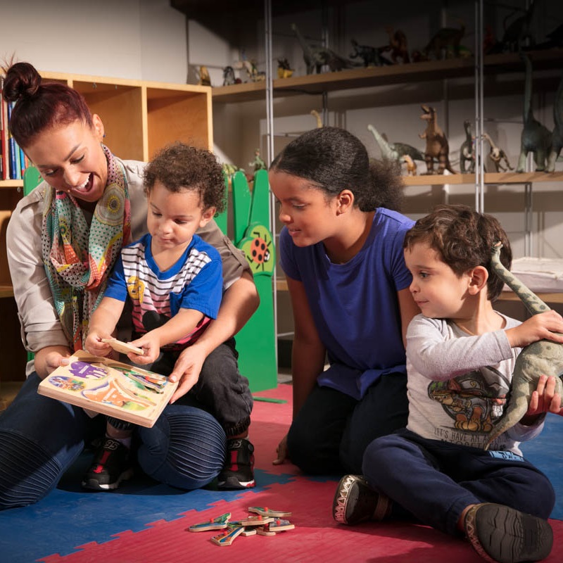 teacher with kids playing with dinosaur toys